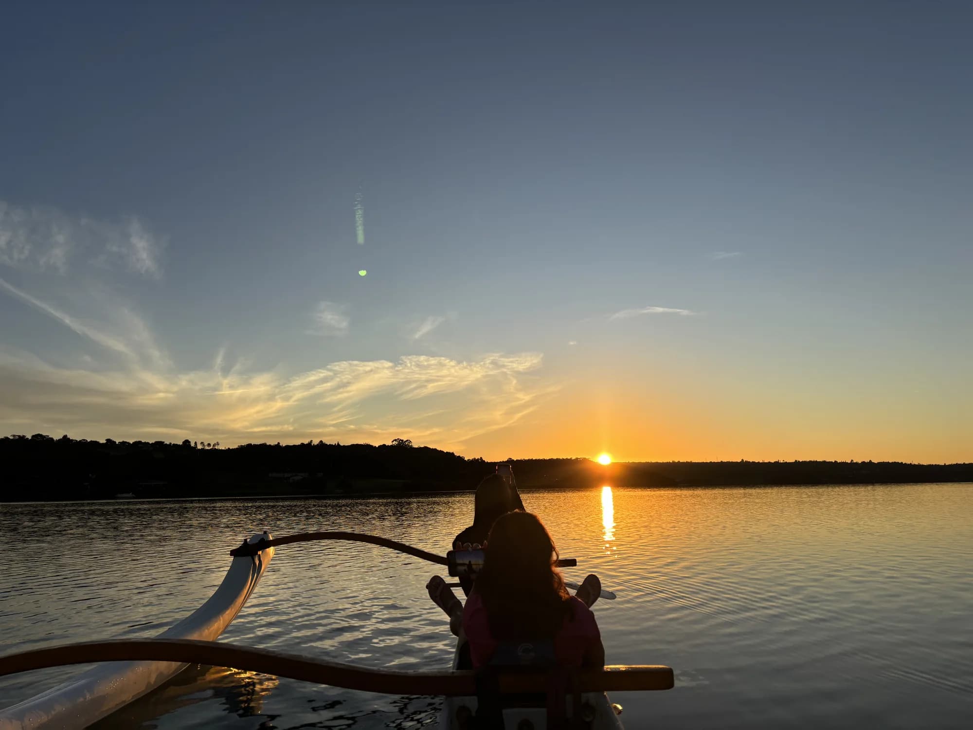 Sol nascendo diante de uma canoa havaiana no Lago Paranoá