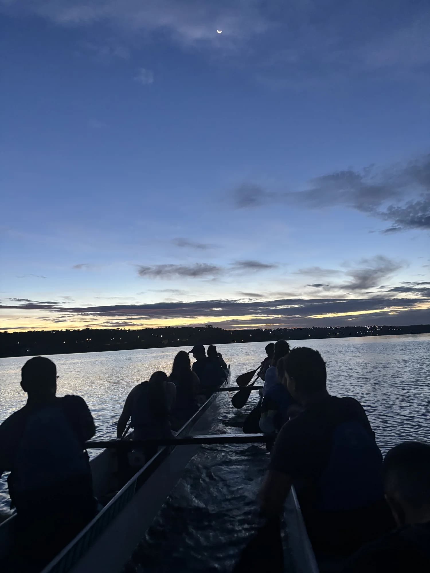 Grupo reunido em uma canoa havaiana sob o céu azul do amanhecer