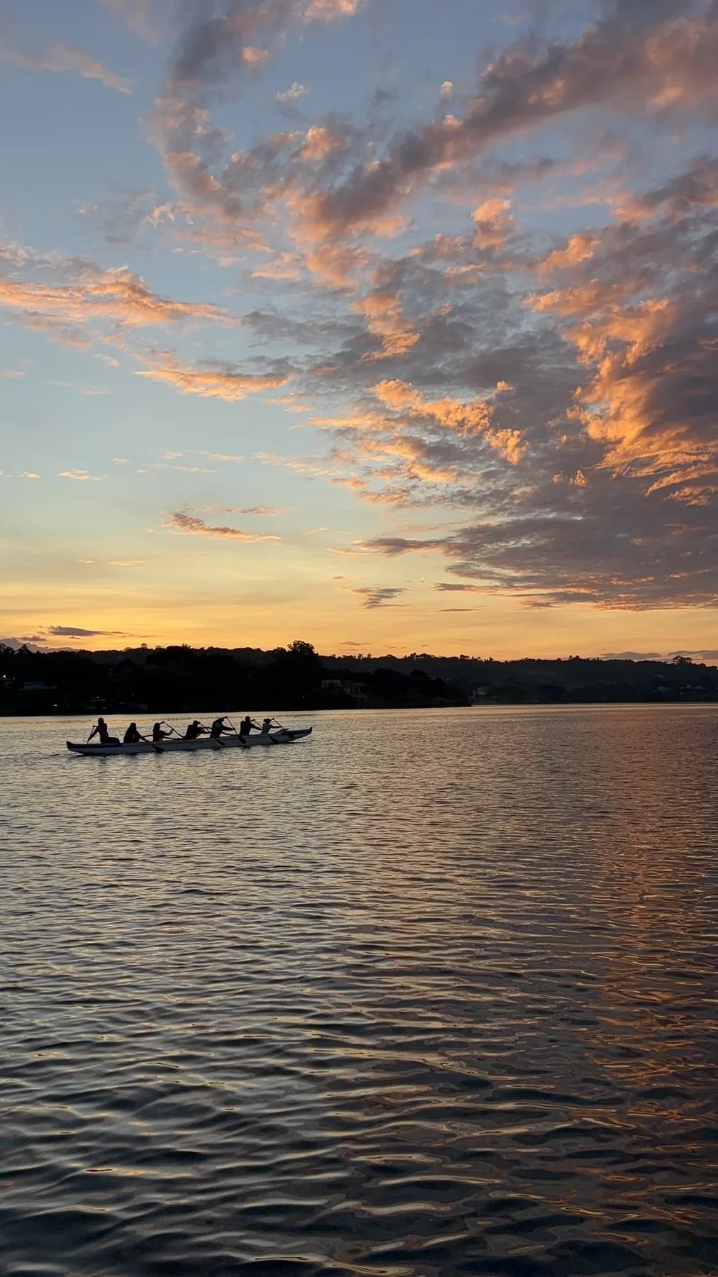 Canoa havaiana navegando no Lago Paranoá sob o céu colorido da manhã