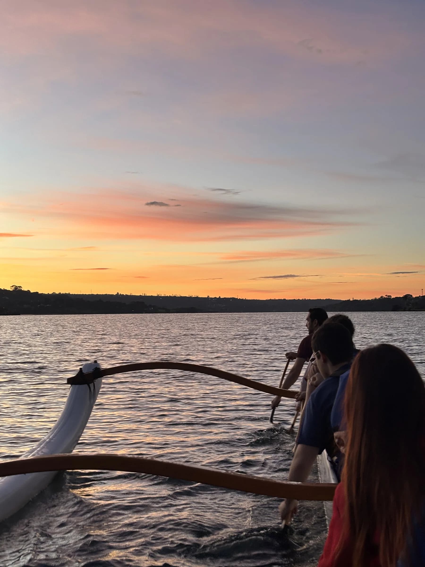Participantes remando em uma canoa havaiana nas primeiras luzes da manhã