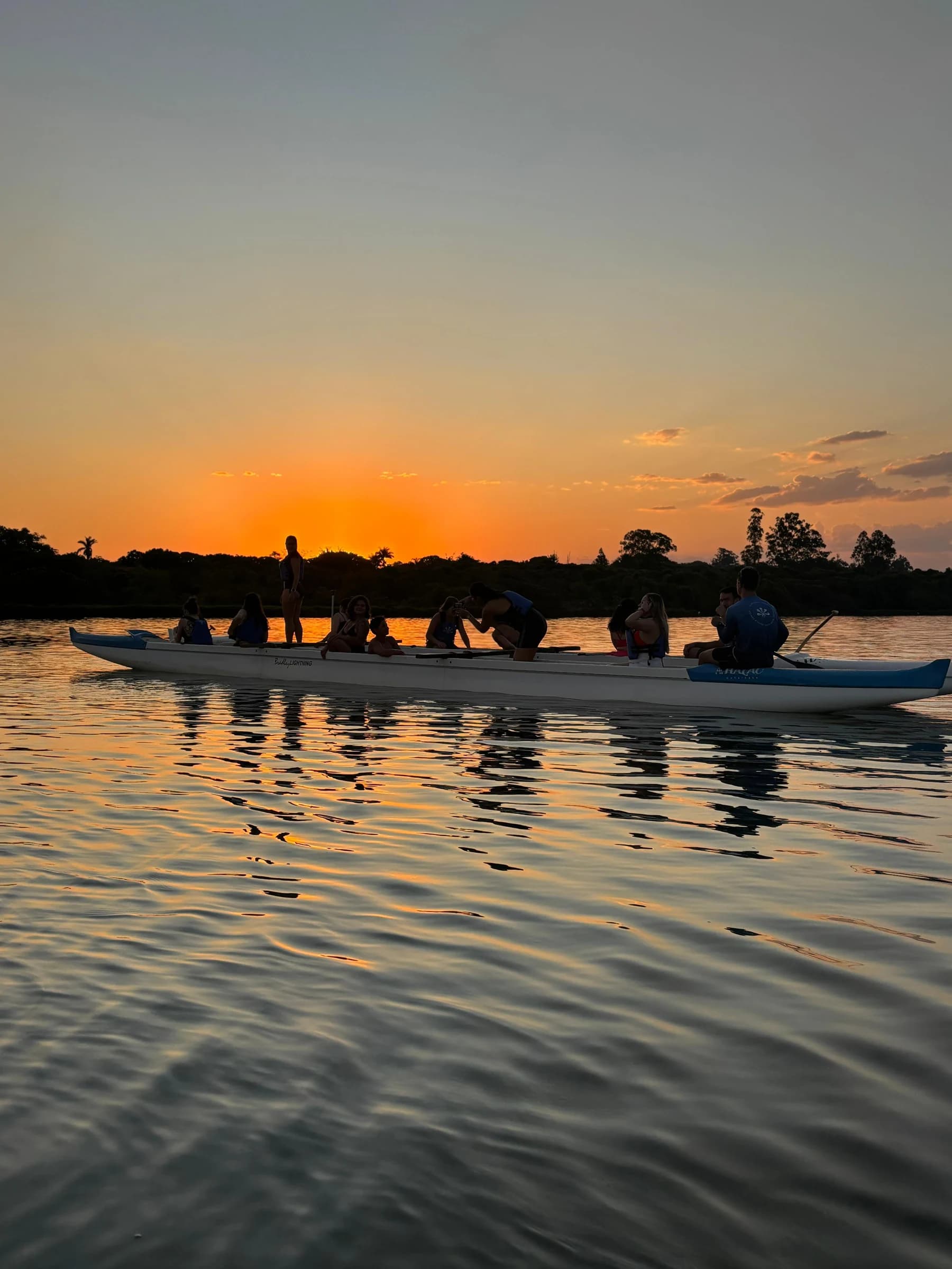 Canoa havaiana navegando no Lago Paranoá durante o pôr do sol