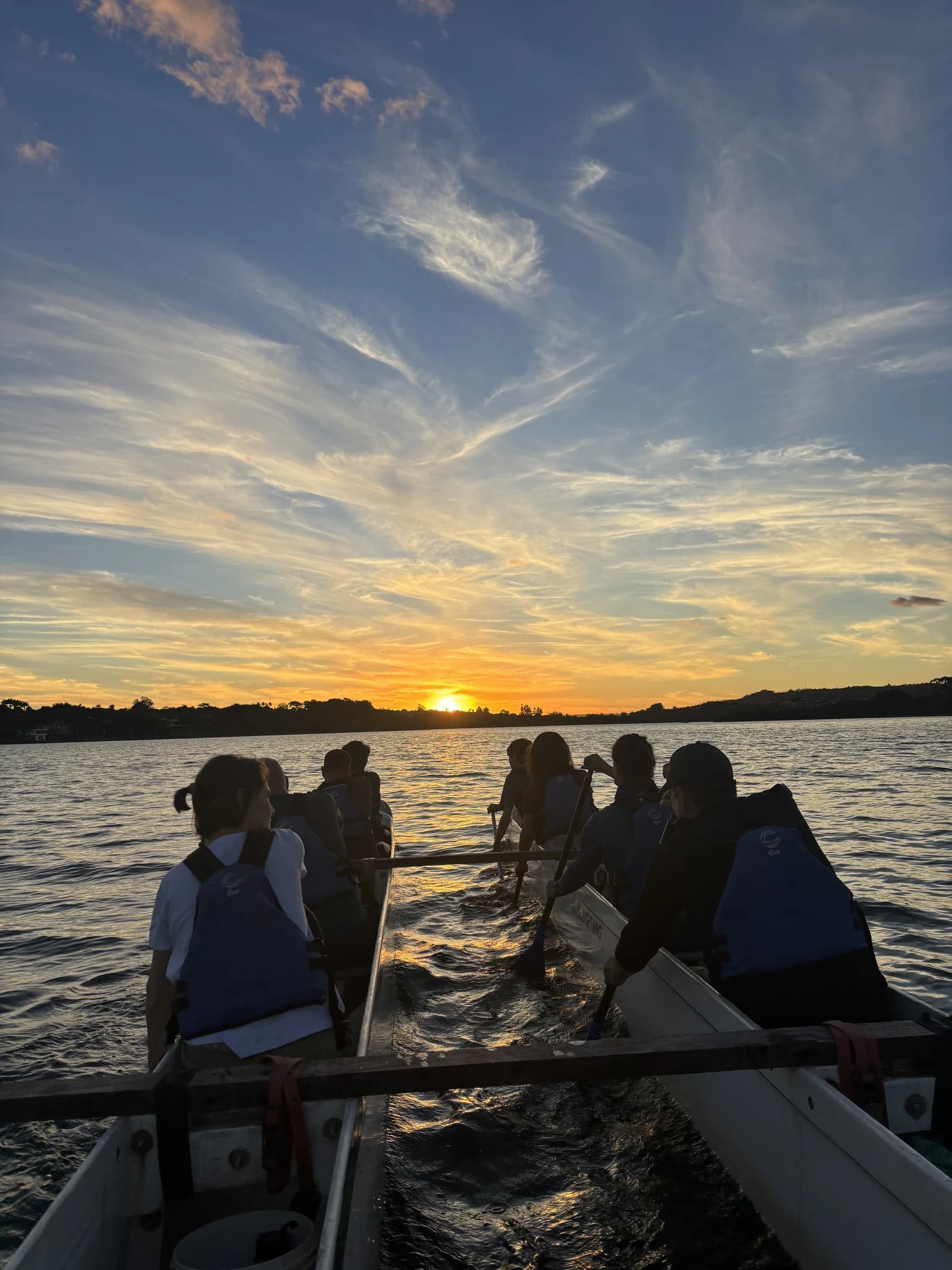 Grupo remando em direção ao pôr do sol no Lago Paranoá