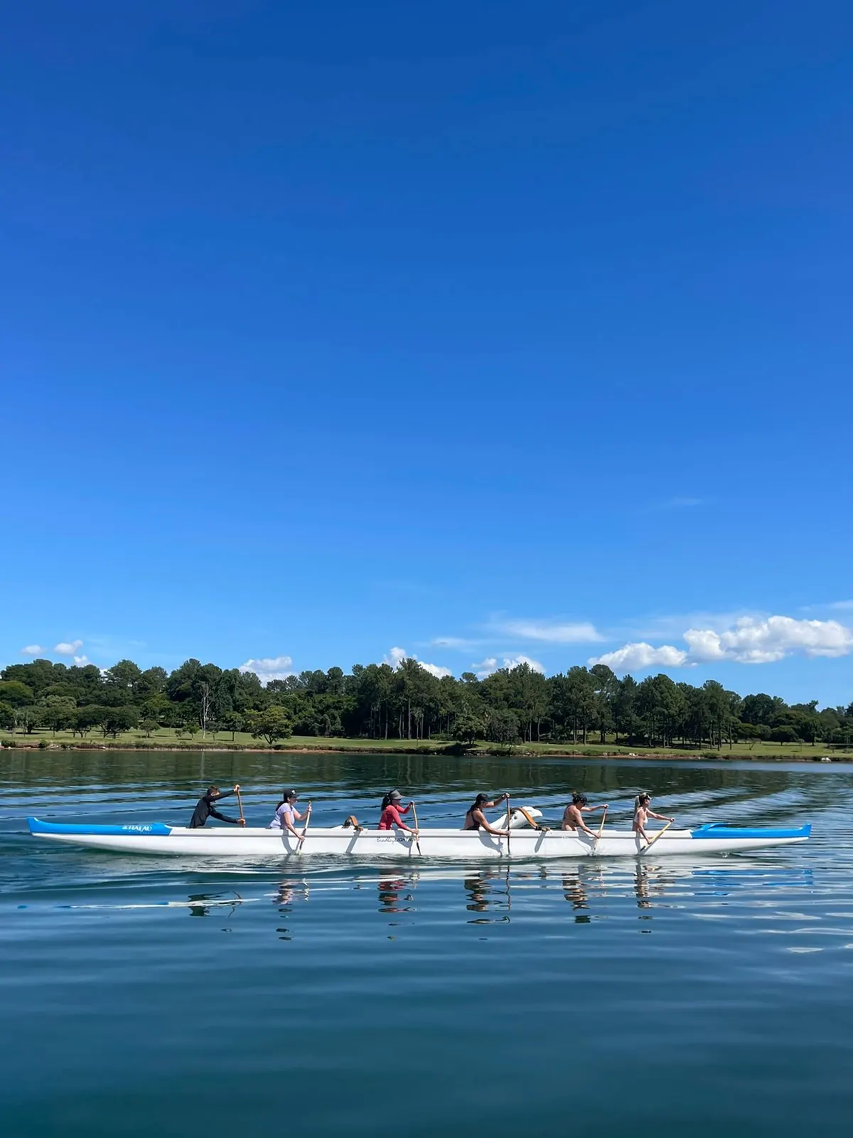 Canoa havaiana da Alma Azul navegando em um dia de céu azul no Lago Paranoá
