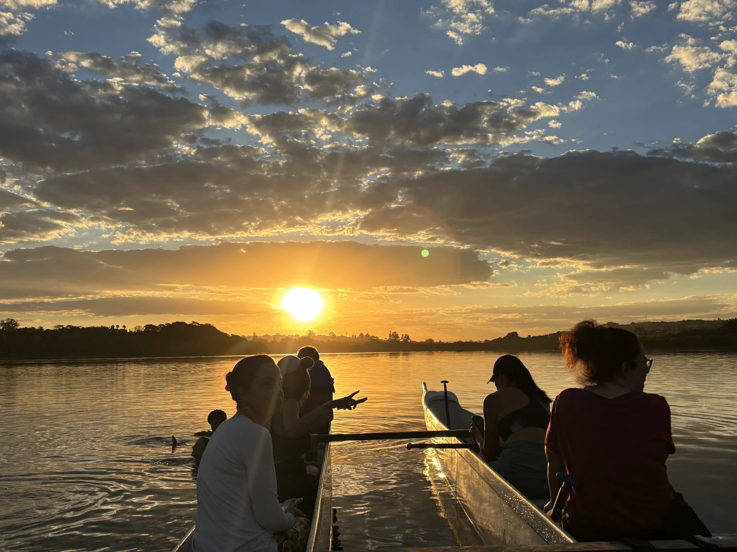 Participantes ao lado das canoas durante o pôr do sol no Lago Paranoá