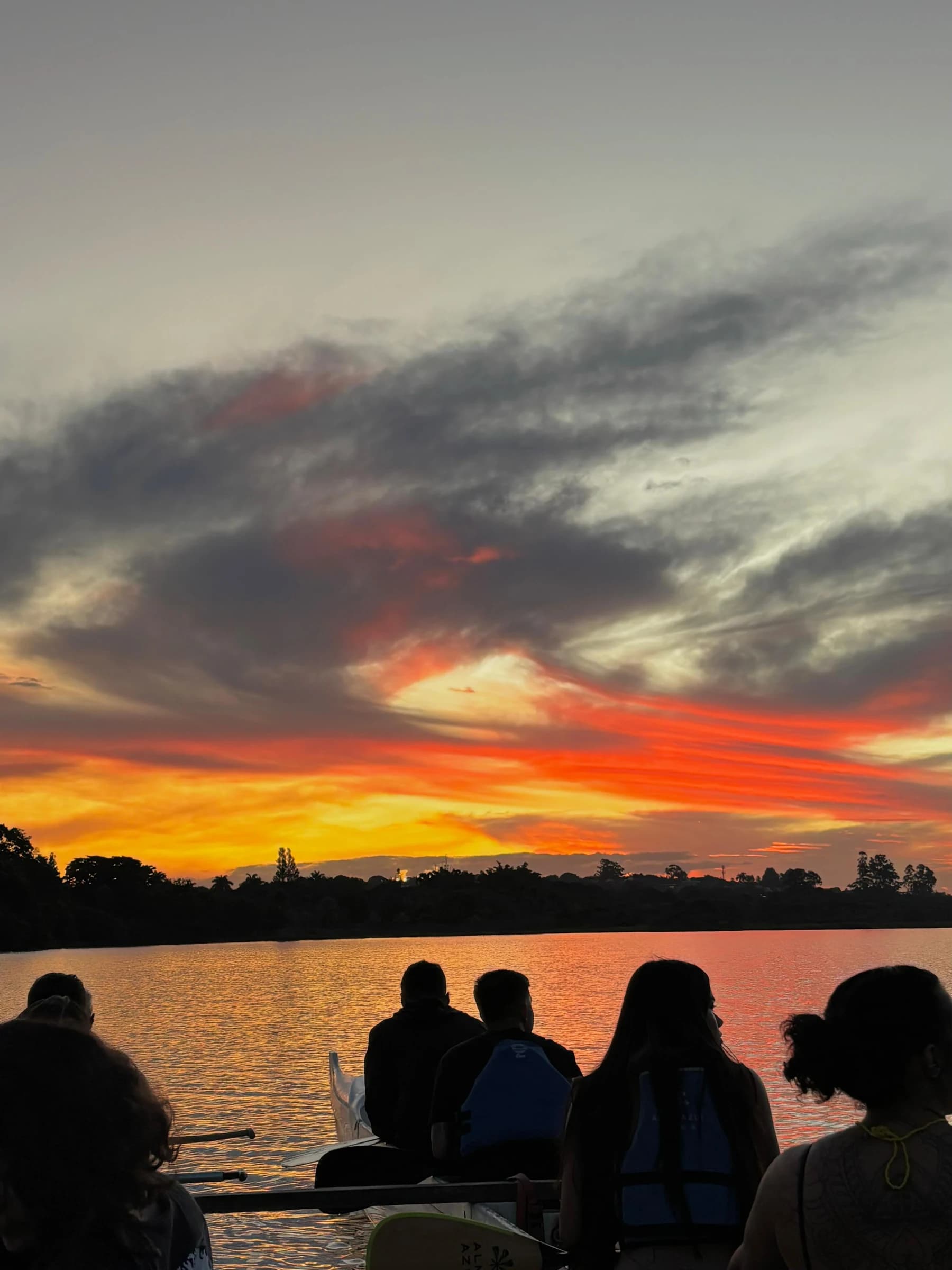 Grupo em uma canoa no Lago Paranoá sob o céu colorido do entardecer